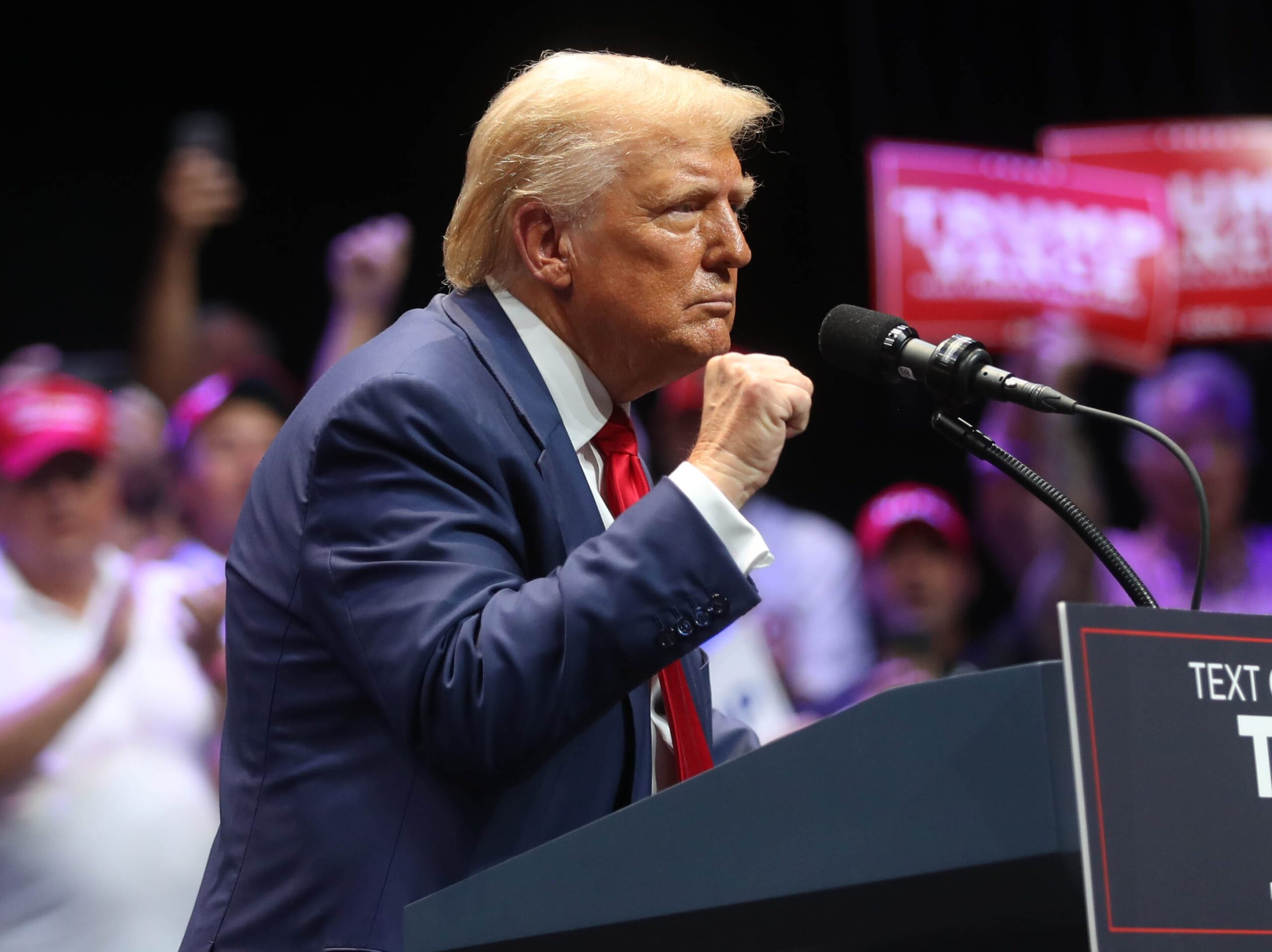 El expresidente Donald Trump levanta el puño mientras pronuncia un discurso en el Teatro Johnny Mercer en Georgia.